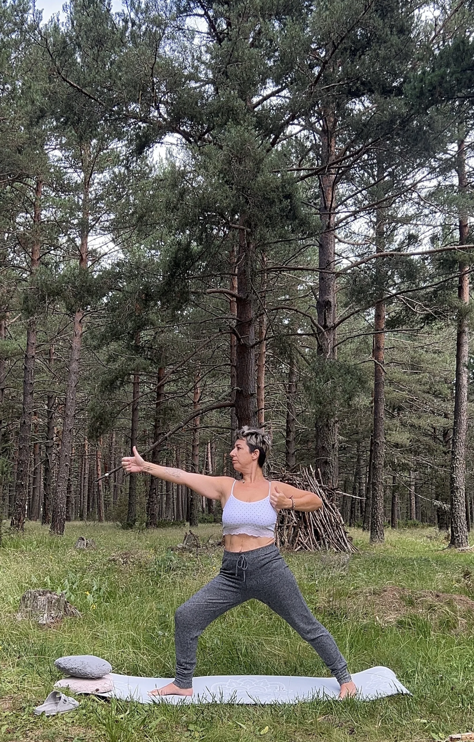 Rosa Pilar de Estética Mima't realizando la postura de yoga del arquero en el bosque. Actividad de movimiento consciente para el Retiro en el Baix Llobregat, cerca de Martorell y Abrera.